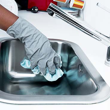 Image of a hand cleaning a stainless steel sink