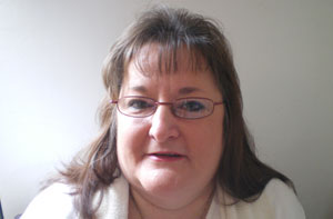 Image of a woman with shoulder length hair and glasses facing the camera