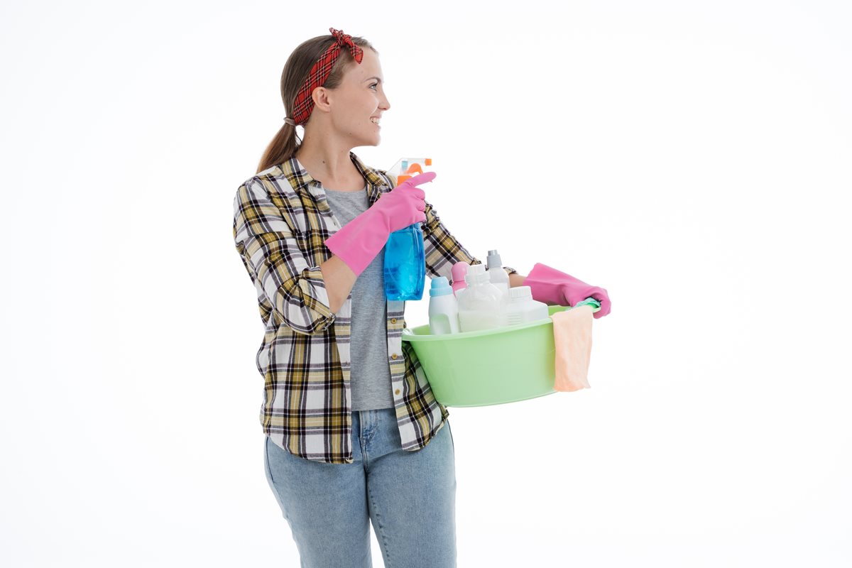 Image of a woman facing to the right dressed as a cleaner and holding a a number of cleaning tools, etc.