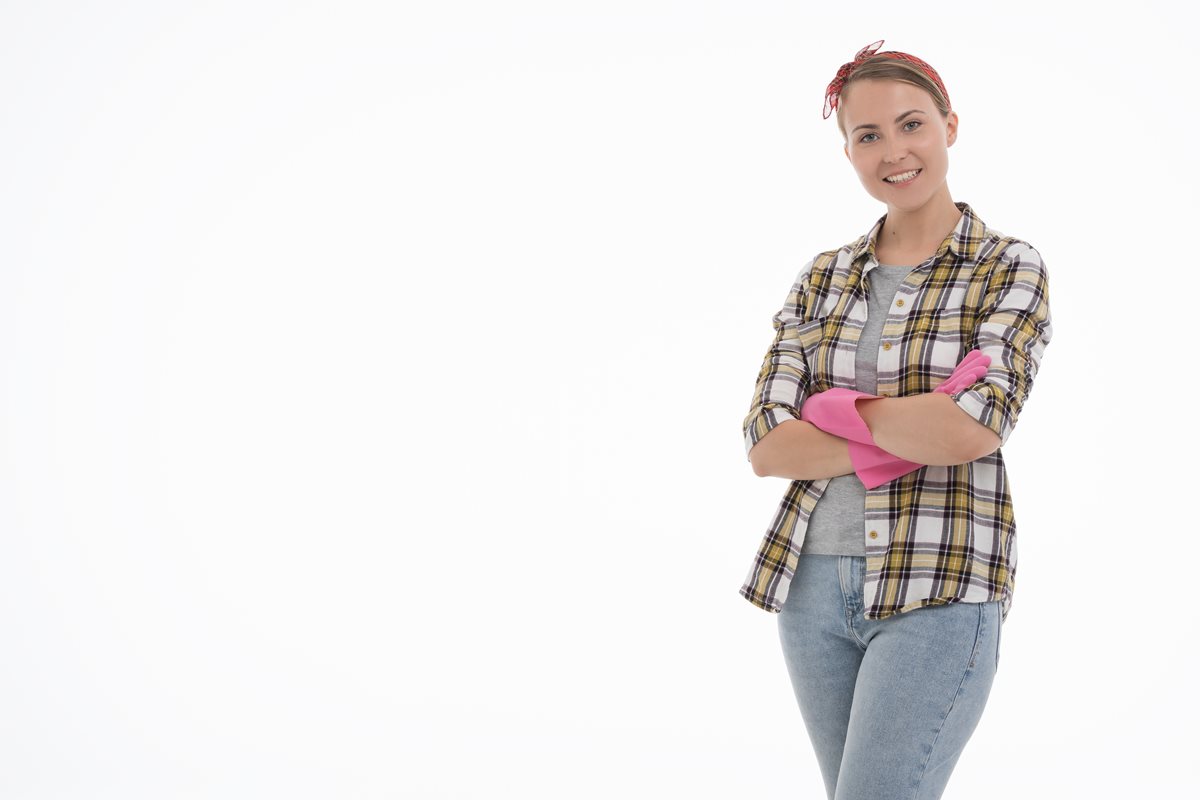 Image of a woman facing the camera dressed as a cleaner and with her arms crossed, as if waiting