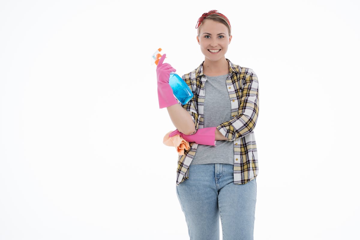 Image of a woman facing the camera dressed as a cleaner and holding a bottle of cleaning solution and a cloth