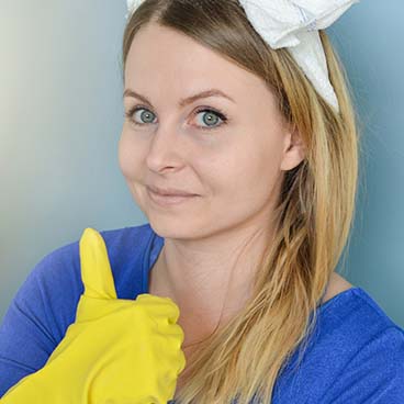 Image of a woman facing the camera dressed as a cleaner and holding one thumb up